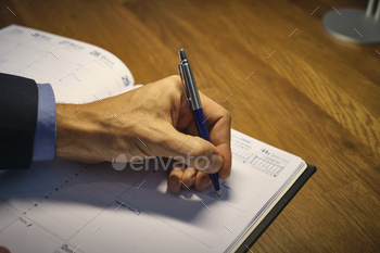 Hand holding a pen writing on a journal