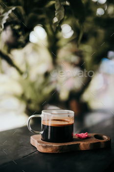 Coffee glass on a wooden board filled with coffee.
