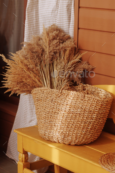 Dried flowers in basket on yellow bench.