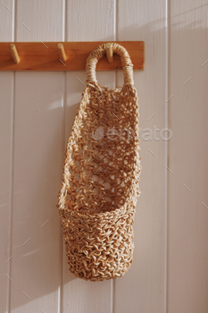 Woven basket hanging on a wooden peg.