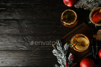 Glasses with apple cider, branches of christmas tree and apples on dark wooden background