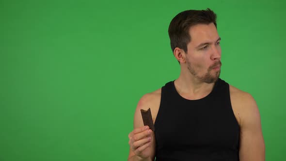 A Young Handsome Athlete Eats a Protein Candy Bar - Green Screen Studio