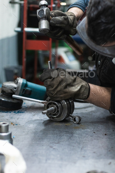 Anonymous repairman fixing motorbike crankshaft bearing in workshop