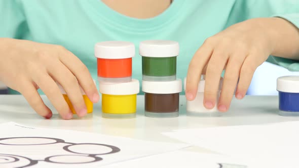 Child Exhibits Various Interesting Figures with Multicolored Paints. Close Up alt