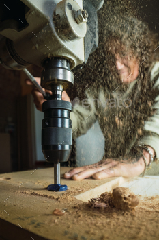 Woodworker using drilling machine in joinery