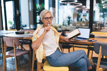 Pensive senior woman with notebook and laptop
