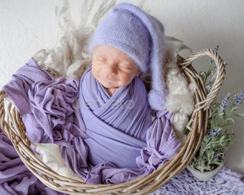 Newborn Baby In Lilac Wrap Sleeps In Basket