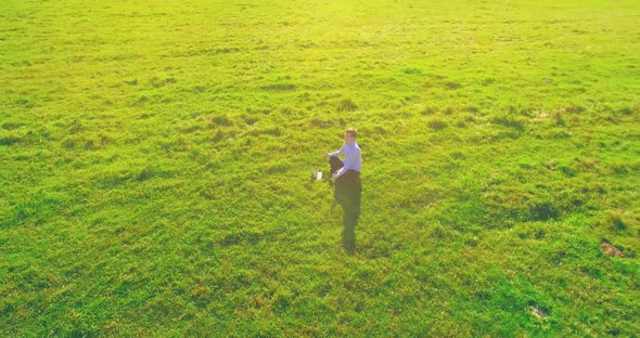 Low Orbital Flight Around Man on Green Grass with Notebook Pad at Yellow Rural Field