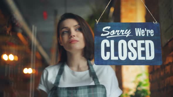 Attractive Young Waitress Changing Closed To Open Sign on Cafe Door Smiling