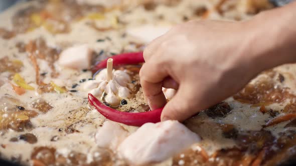 Closeup Chef Hand Adding Hot Spice Chilli Pepper to Boiling Dish