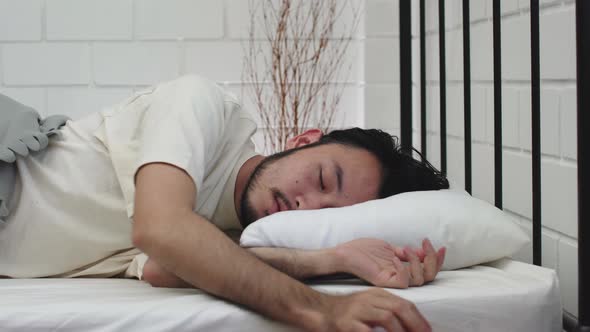 lazy overwork tired asian man on white bed bore to wakeup try to stop alarmclock
