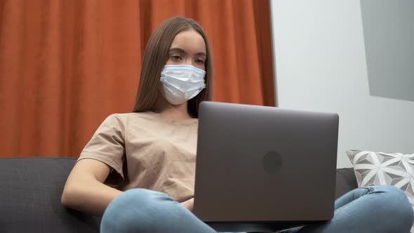 Young Woman Wearing Face Protective Medical Mask for Protection From Virus Disease with Laptop