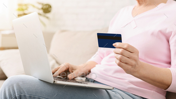 Woman Sitting on Couch Holding Credit Card and Laptop