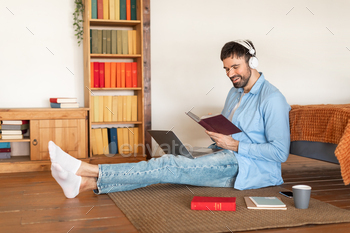 Man Sitting on Floor With Book and Laptop