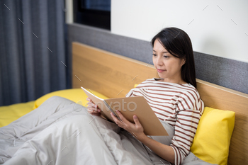 Woman read on the notebook on bed