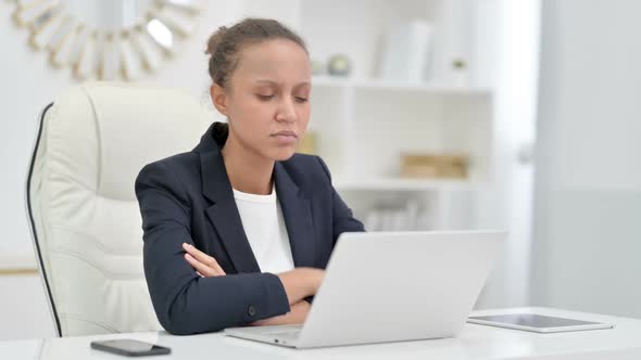 Pensive African Businesswoman Thinking and Working on Laptop in Office