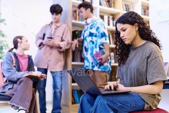 Girl using Computer in Library with Group of Students