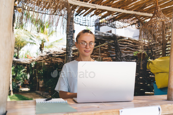 Content woman with notebook working on laptop