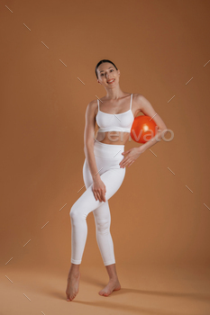 Fitness ball in hand. Beautiful fitness woman is in the studio