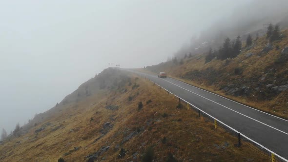 Aerial Shot of Orange Car Riding Through Mountain Road at Autumn