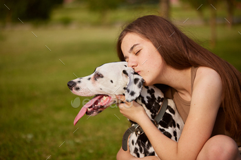 girl kissing dalmatian dog in the park, love for dog and animals