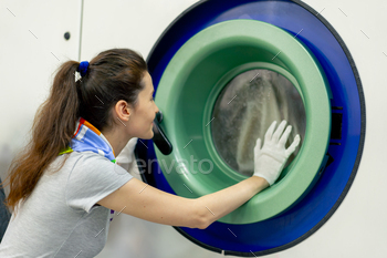 professional dry cleaner young girl watches the washing process of a professional machine