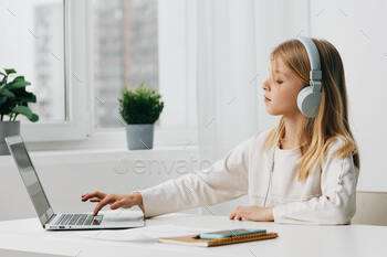 Smiling Girl Engaged in ELearning at Home with Laptop and Headphones