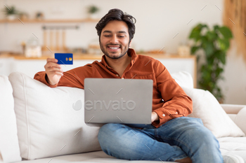 Man Sitting on Couch With Laptop and Credit Card