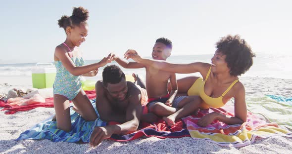 Smiling african american family lying on towels on sunny beach