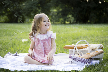 Cheerful girl sitting with picnic basket in park