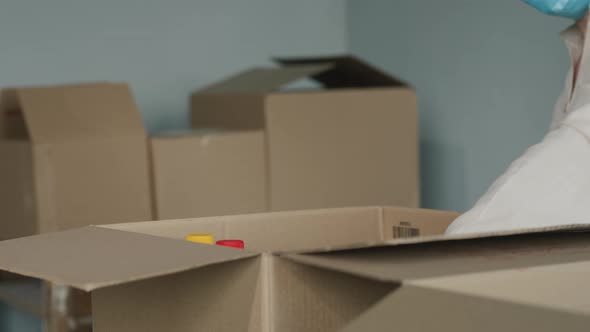 Volunteer's Hands in Protective Gloves Put Food in a Shipping Box