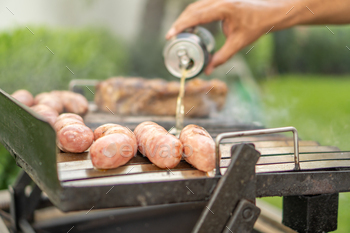 Man marinating meat with beer on a barbecue