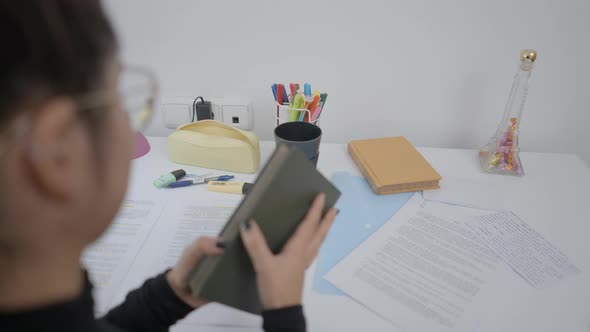 A Young Student of Colombian Universitary Sitting at a Study Table and Reading a Book