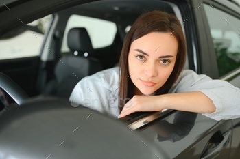 Photo of happy young woman sitting inside her new car. Concept for car rental