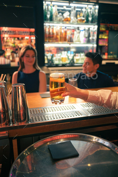 Bartender serving a glass of beer in a busy nightclub