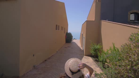 Young girl running on luxury villa.Woman dressed in white dress and hat
