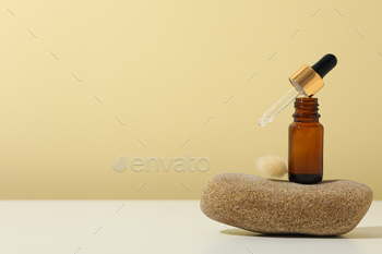 Cosmetic oil in a brown bottle with a pebble