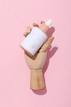 A cosmetic bottle in a mannequin's wooden hand