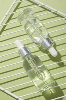 Transparent cosmetic bottles on a green background