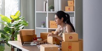 Small business owner preparing packages for shipment at home office. Concept of ecommerce, online