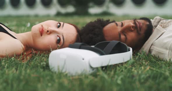 A young couple lying on the grass with virtual reality glasses