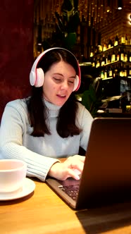 Woman Freelancer Working in Cafe Listening Music in Headset