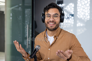 Young man hosting a podcast with headphones and microphone in modern studio