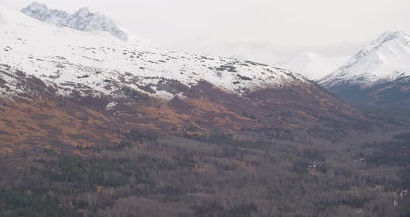 Aerial helicopter shot of Alaskan river alongside highway and towards powerlines, drone footage