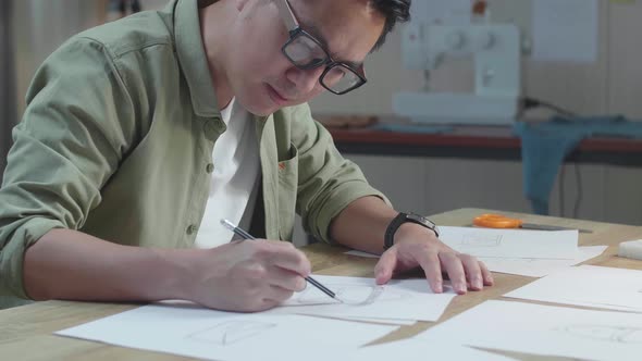 Close Up Of Asian Man Designer Sketching Hand Bag On The Layout Bond At The Office