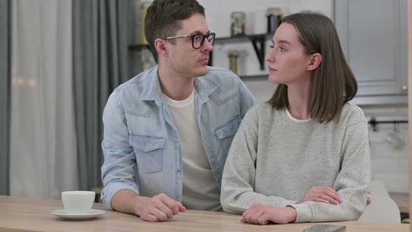 Disappointed Young Couple Doing Thumbs Down at Home 