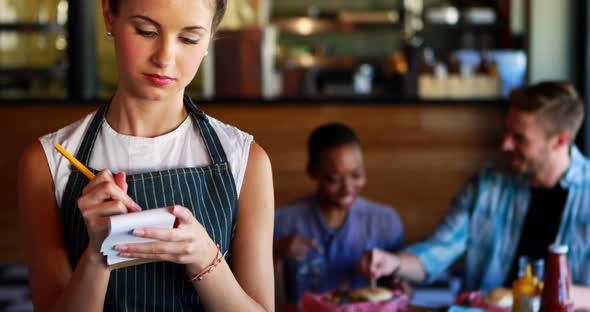 Portrait of waitress noting order on notepad