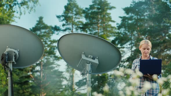 Woman Tunes Satellite Dishes Outdoors Uses Tablet