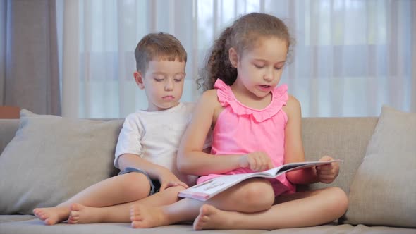 Cute Children,sister with a Younger Brother, Looking at a Book Magazine Textbook Dictionary Tablet