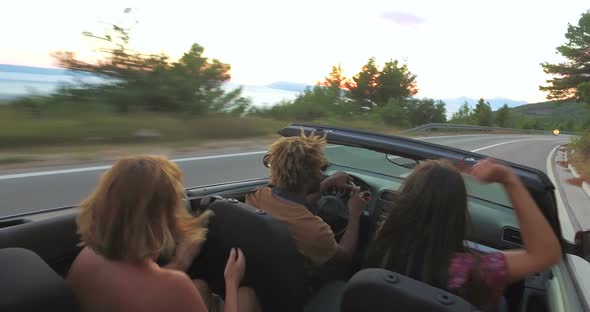 Young friends enjoying their road trip in convertible car